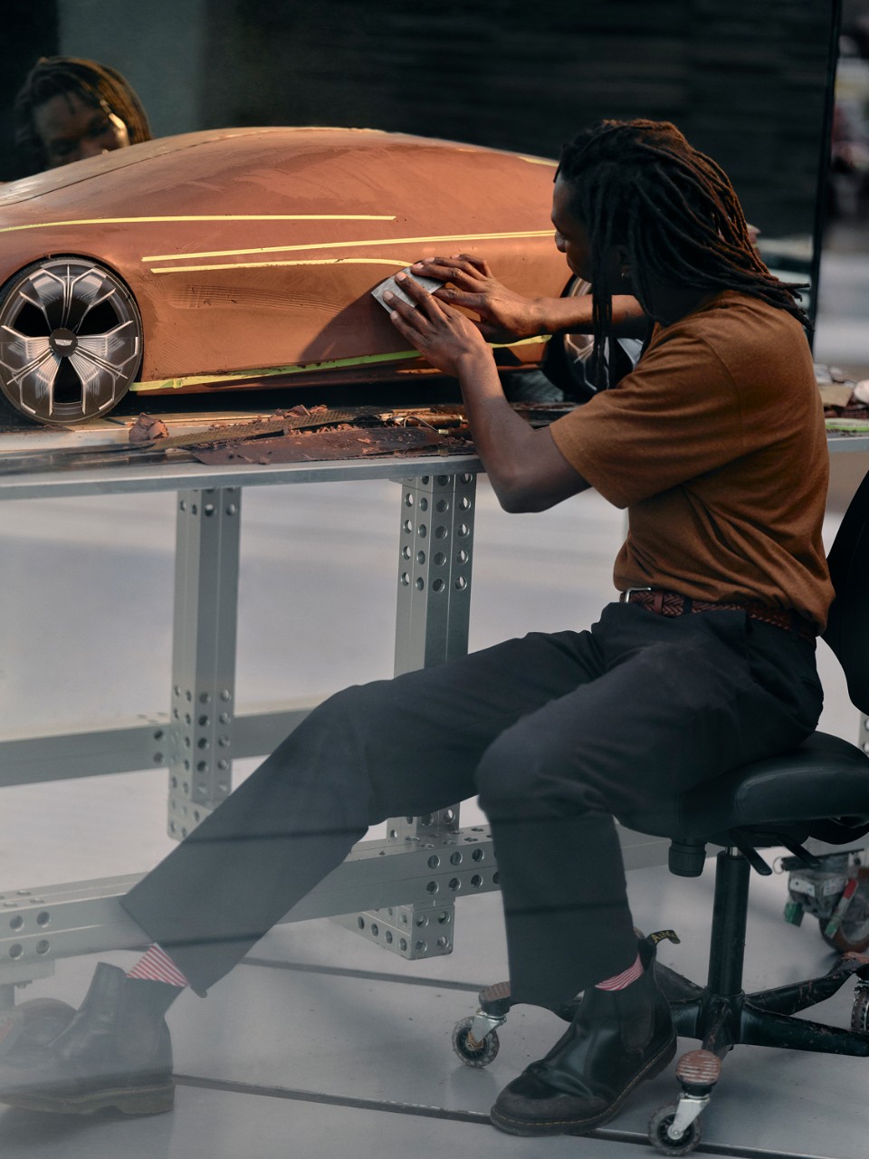 Automotive designer sculpts clay model of a vehicle by hand. refining the vehicle's frame in an automotive design studio.